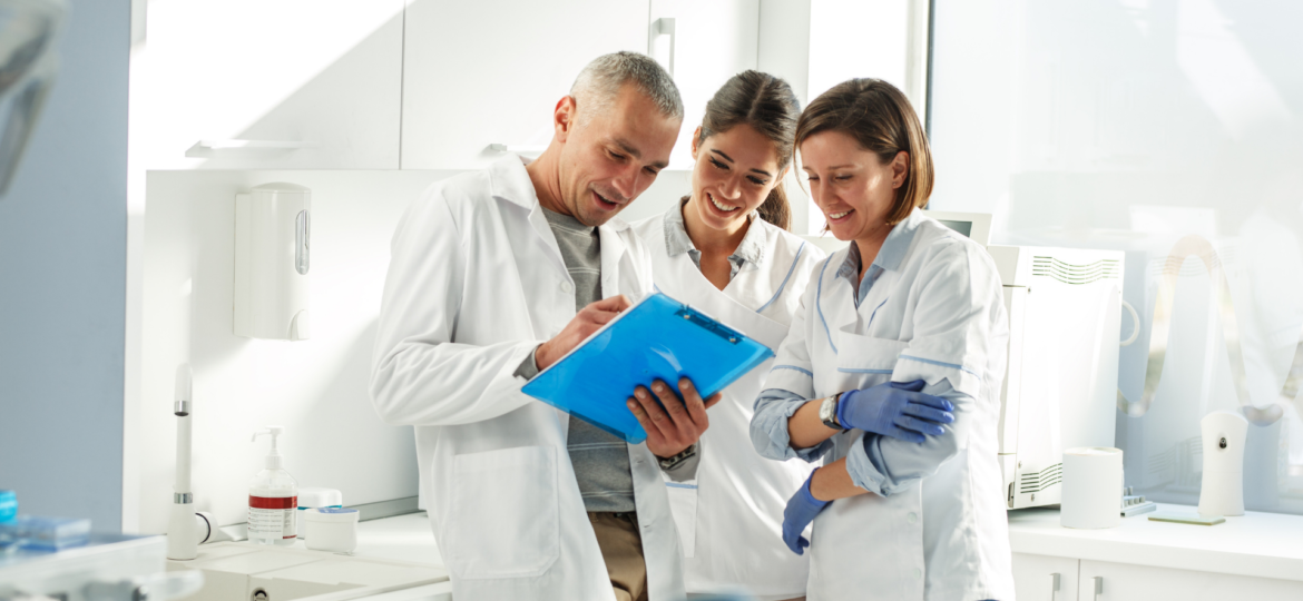 Photo of three dental professionals looking over a clip board.