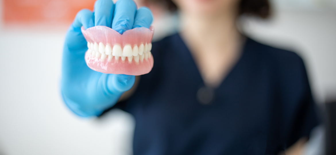 Trends in Dentistry Blog Graphic: Photo of dental assistant holding up dentures.